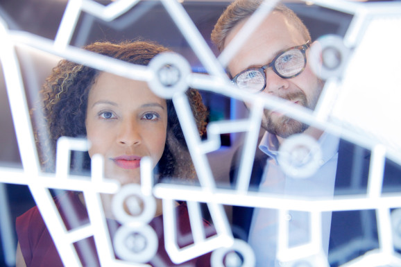 Two people consult over a large data screen
