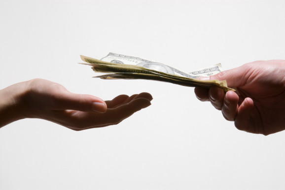 Man handing another person US dollar banknotes, close-up