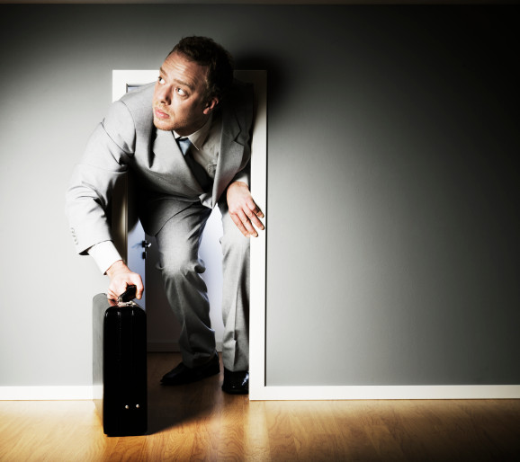 Businessman trying to fit through a very small door.