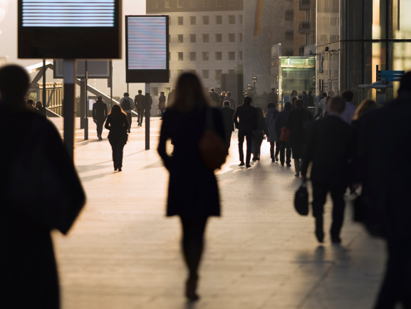 silhouttes of people in concrete cityscape with black and white digital billboards overhead