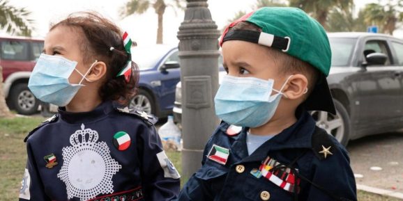 Kuwaiti kids wear protective face masks, following the outbreak of coronavirus, during celebrations of the 29th Kuwait Liberation Day from the Iraqi occupation, in Kuwait on February 26, 2020.