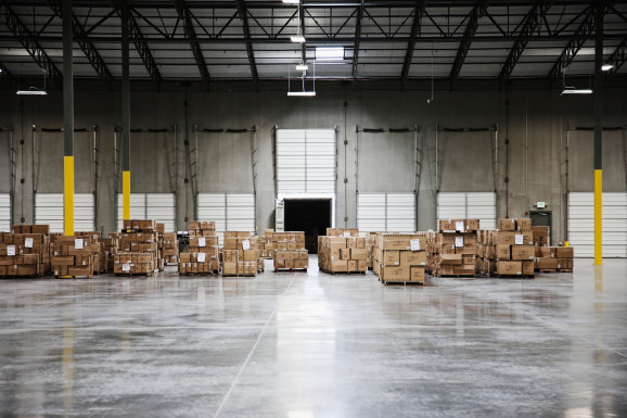A few stacks of boxes sit in a mostly empty warehouse