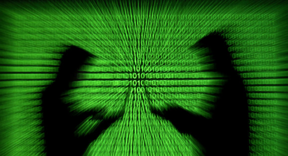 Silhouettes of laptop users are seen next to a screen projection of binary code are seen in this picture illustration taken March 28, 2018.