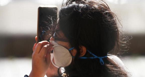 A woman holds a mobile phone while the spread of the coronavirus disease (COVID-19) continues, London, Britain, April 19, 2020.