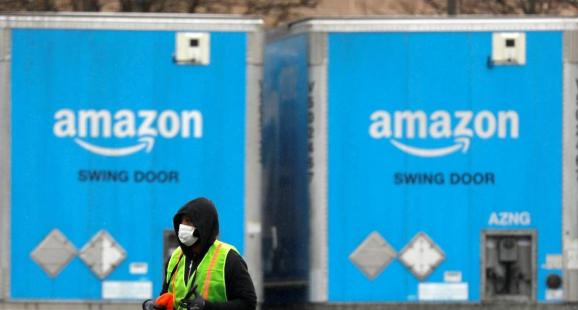A worker in a face mask walks by trucks parked at an Amazon facility as the global coronavirus outbreak continued in Bethpage on Long Island in New York, U.S., March 17, 2020.