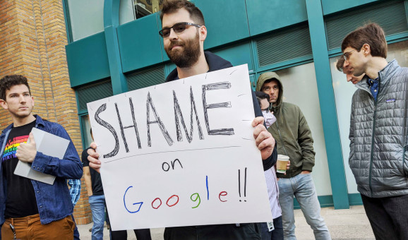 Adam Campbell holds a protest sign that reads Shame on Google