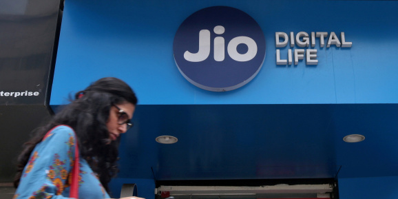 A woman checks her mobile phone as she walks past a mobile store of Reliance Industries' Jio telecoms unit, in Mumbai, India