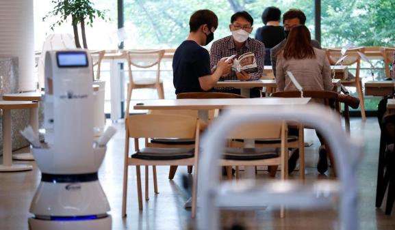 Customers wait at a cafe where a robot that takes orders, makes coffee and brings the drinks straight to customers is being used in Daejeon, South Korea, May 25, 2020.