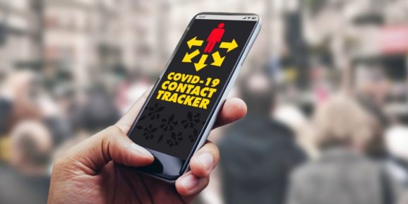 hand holding a smartphone with a contact tracing app loaded, on busy sidewalk