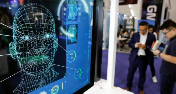 Visitors check their phones behind the screen advertising facial recognition software during Global Mobile Internet Conference (GMIC) at the National Convention in Beijing, China April 27, 2018.
