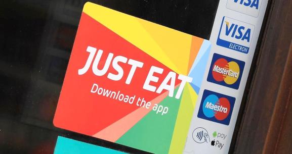 Signage for Just Eat is seen on the window of a restaurant in London, Britain, August 5, 2019.