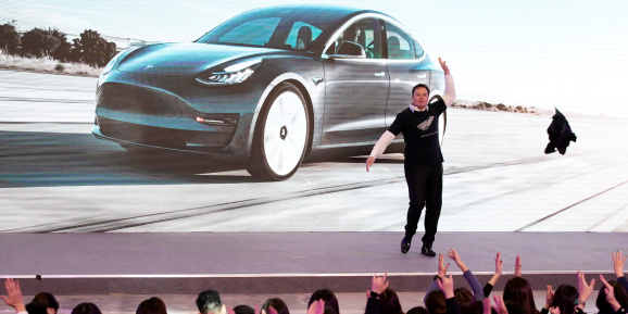 Tesla CEO Elon Musk takes off his coat onstage during a delivery event for Tesla China
