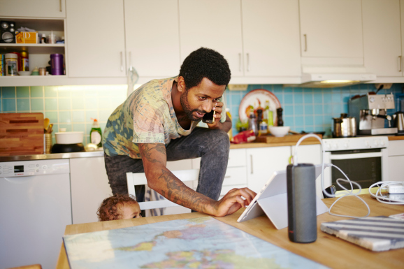 Father and son in kitchen juggling multiple devices