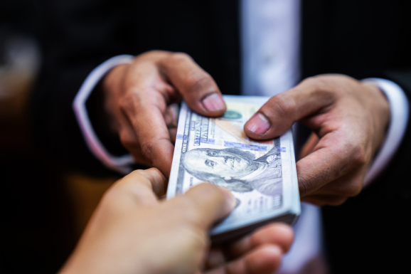 Businessman giving bribe money  to partner in a corruption scam with black  tone,corruption
